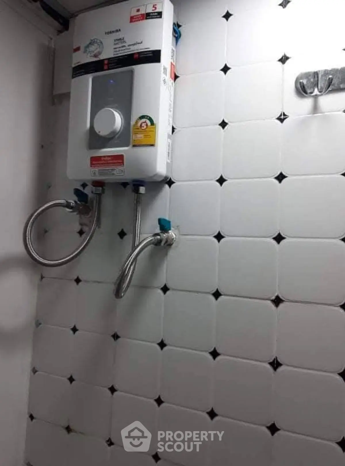 Compact bathroom with modern water heater and tiled wall.