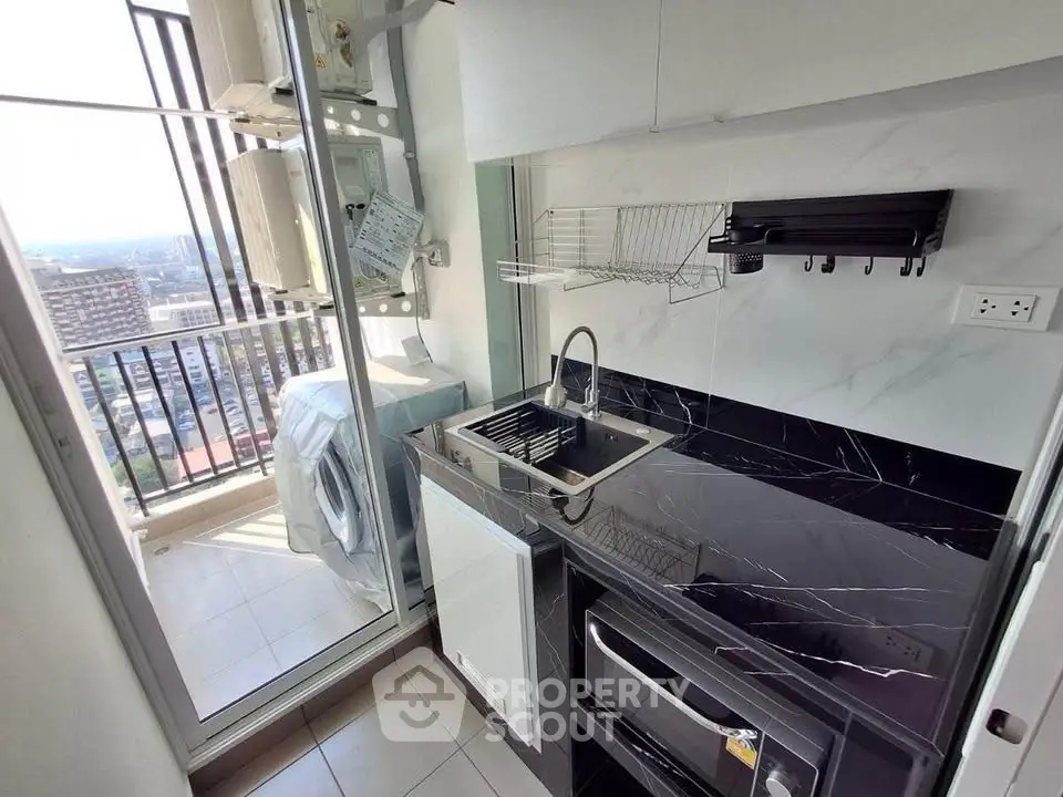 Modern kitchen with sleek black countertops and balcony view