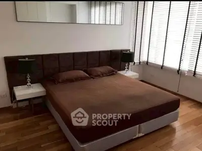 Modern bedroom with stylish decor and natural light, featuring a comfortable bed and elegant lamps.