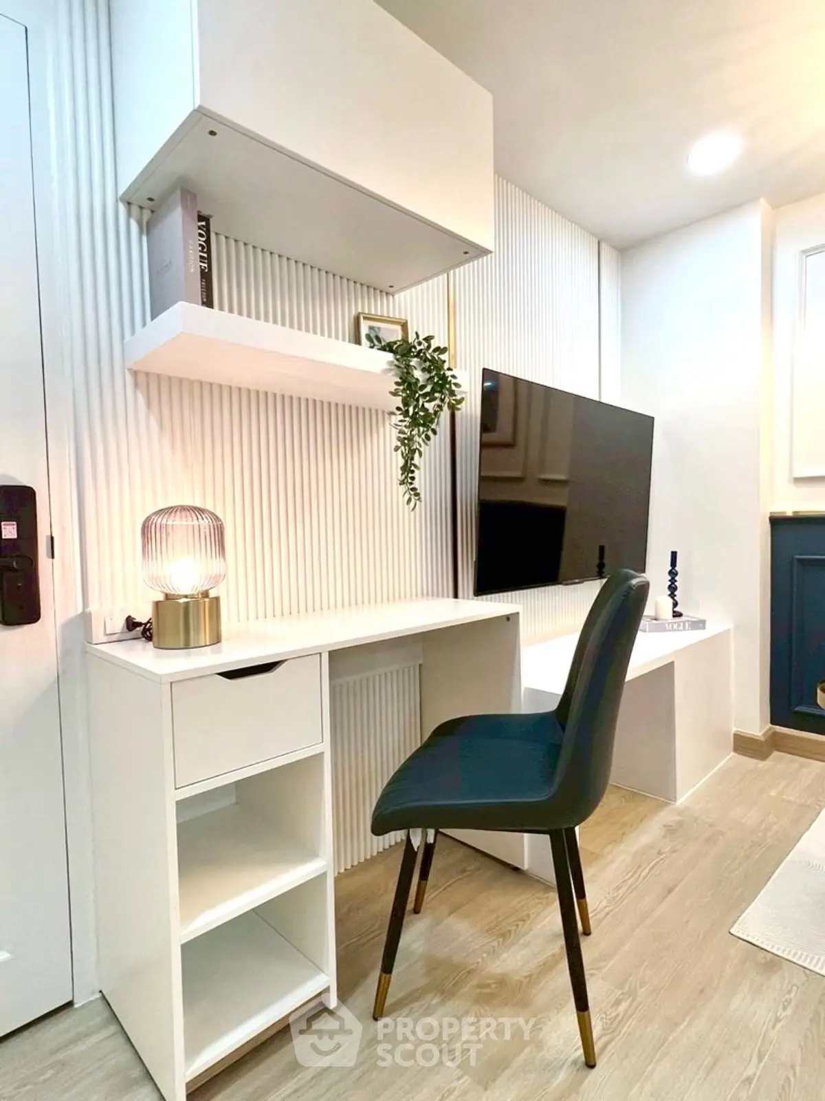 Modern study area with sleek desk, chair, and wall-mounted TV in stylish apartment.