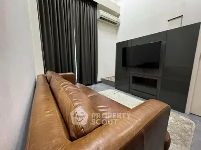 Modern living room with leather sofa and wall-mounted TV, featuring sleek design and cozy ambiance.