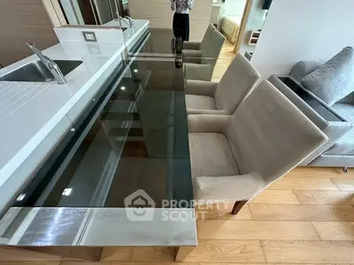 Modern kitchen with sleek glass dining table and plush chairs, showcasing contemporary design and elegance.