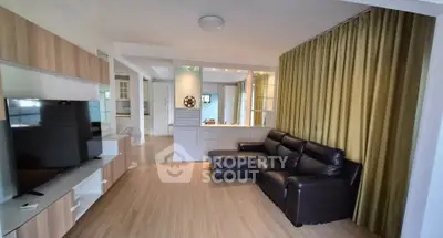 Spacious living room with modern decor and large TV, perfect for relaxation and entertainment.