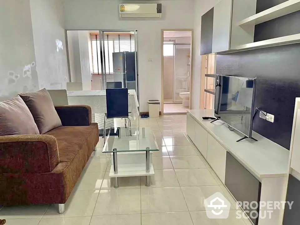 Modern living room with sleek furniture and TV in a cozy apartment setting.