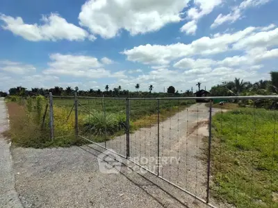 Expansive rural land with gated entrance under a bright blue sky, ideal for development or agriculture.