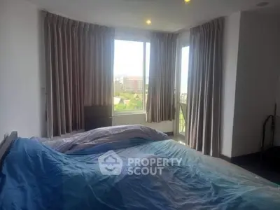 Spacious bedroom with large windows offering a stunning city view, perfect for relaxation and comfort.