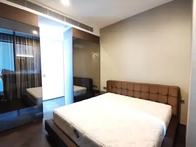 Modern bedroom with stylish decor and large mirror reflecting natural light.