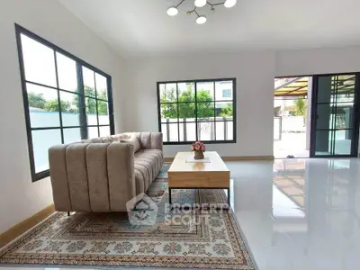 Spacious living room with elegant sofa and large windows offering natural light.