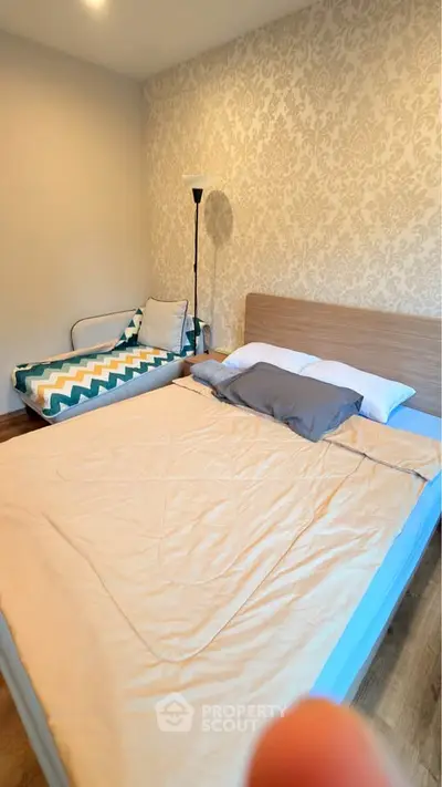 Cozy bedroom with elegant wallpaper and comfortable bedding in a modern apartment.
