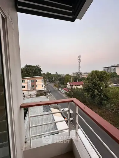 Charming balcony view overlooking a serene neighborhood with lush greenery and distant buildings.