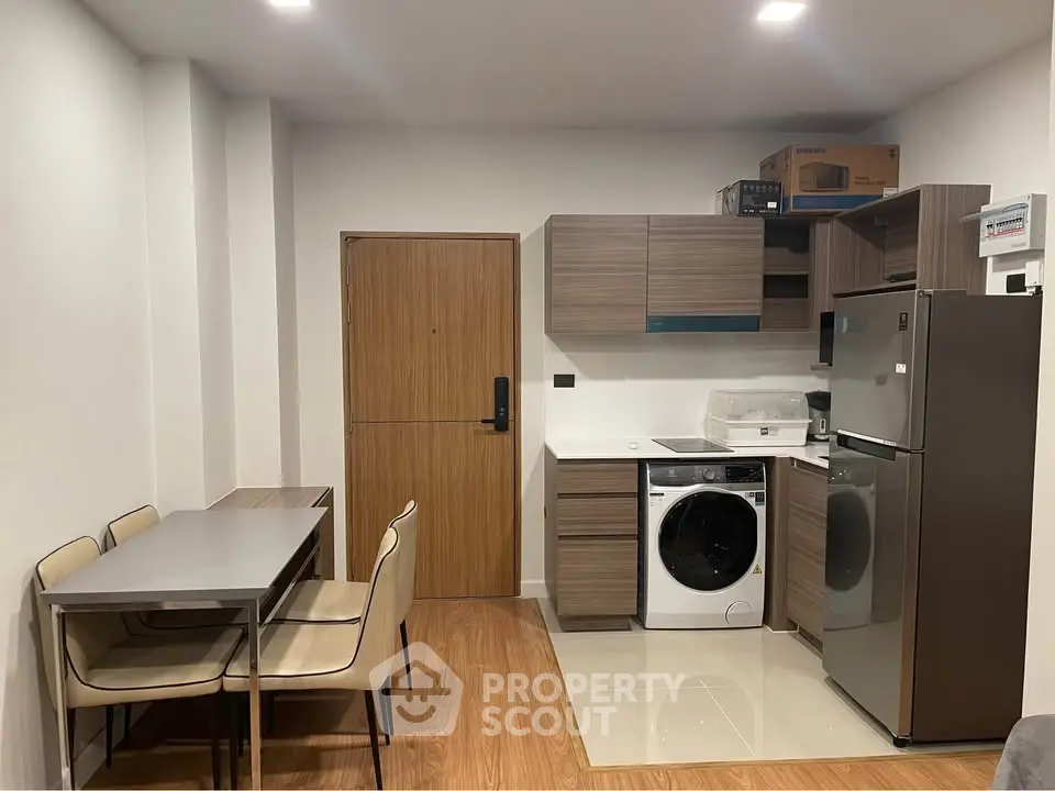 Modern compact kitchen with dining area, featuring washing machine and stainless steel appliances.
