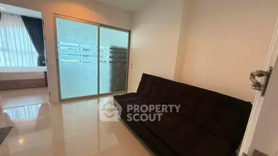 Modern apartment with sleek sliding glass doors and cozy black sofa in bright living area.