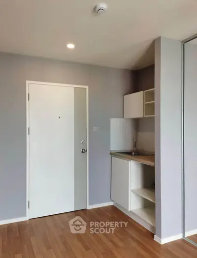 Modern compact kitchen with sleek cabinetry and wooden flooring in a cozy apartment.