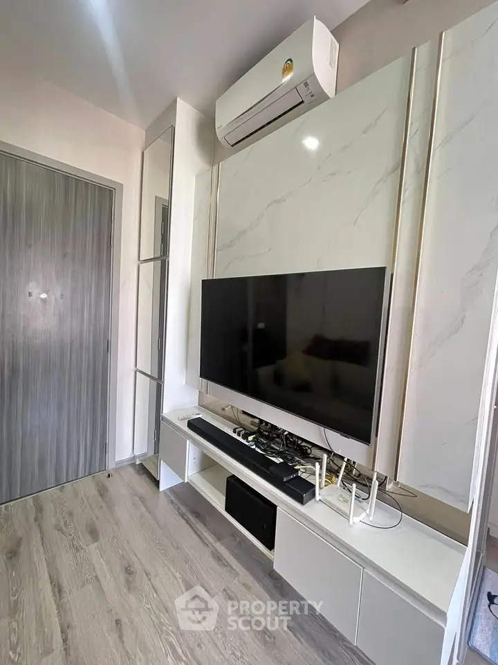 Modern living room with sleek TV setup and air conditioning, featuring stylish flooring and contemporary design.