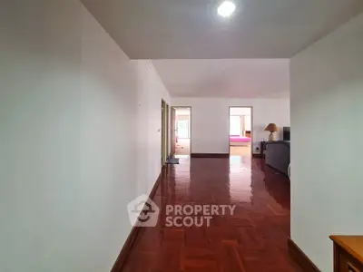Spacious hallway leading to a cozy living room with wooden flooring and ample natural light.