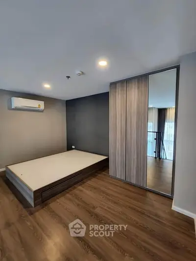 Modern bedroom with wooden flooring and built-in wardrobe, featuring a minimalist design.