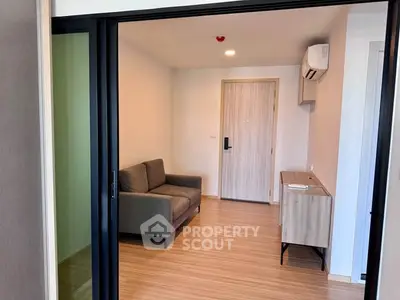 Modern living room with sleek design and wooden flooring, featuring a cozy sofa and air conditioning.