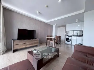 Modern living room with sleek furniture and integrated kitchen appliances in open layout.