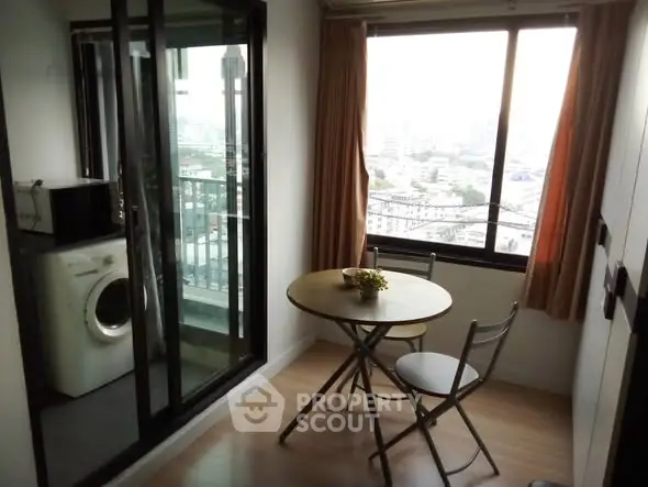 Cozy dining area with city view and adjacent balcony in modern apartment.