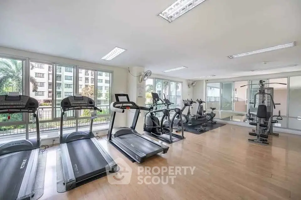 Spacious gym with modern equipment and large windows in a residential building.