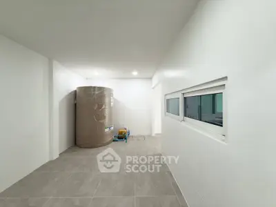 Spacious storage room with large cylindrical container and modern tiled flooring.