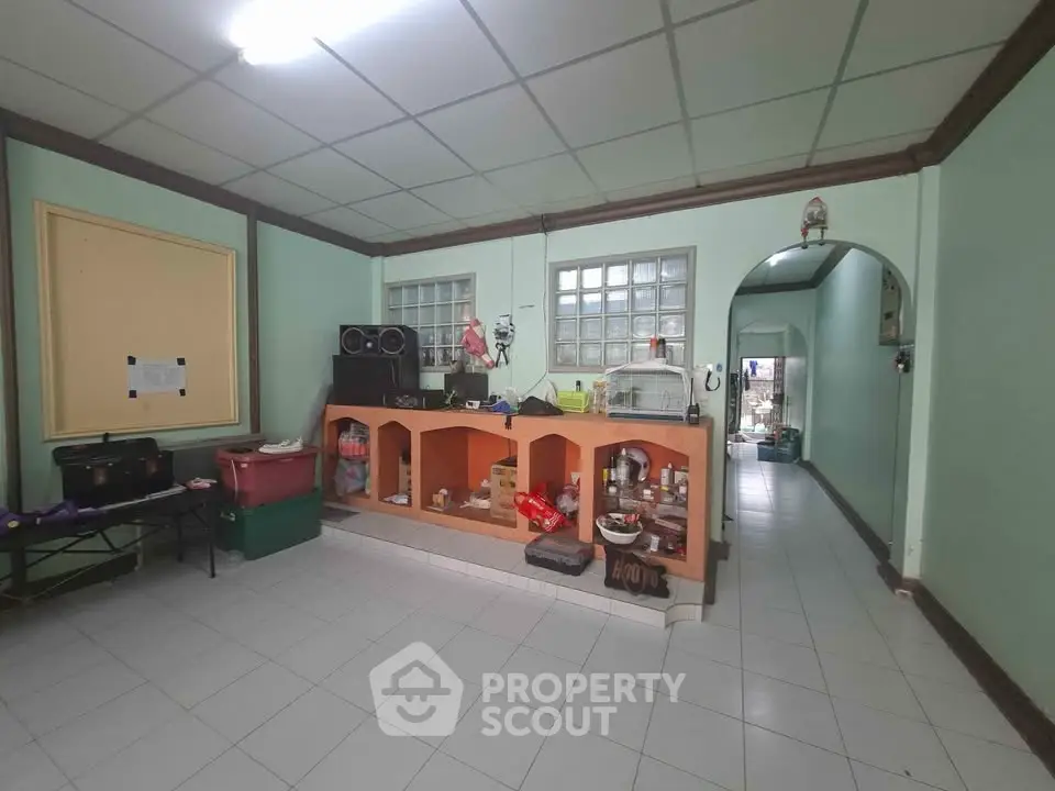 Spacious living room with tiled floor and built-in wooden shelving, ideal for cozy family gatherings.