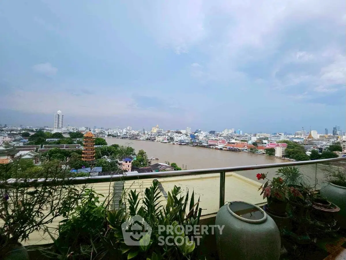 Stunning cityscape view from a high-rise balcony with lush greenery and river panorama.