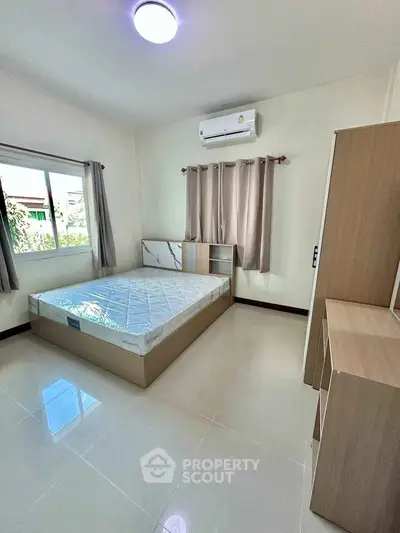 Spacious bedroom with modern furnishings and natural light, featuring a comfortable bed and air conditioning.