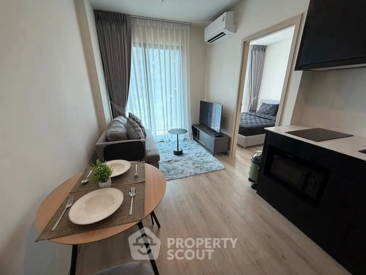 Modern open-plan living room with cozy seating and dining area, featuring natural light and stylish decor.