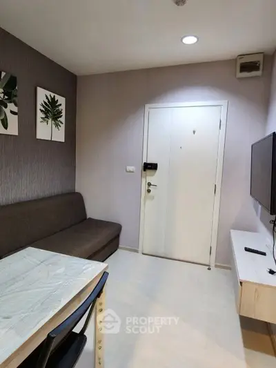 Modern living room with sleek furniture and wall-mounted TV in a cozy apartment.