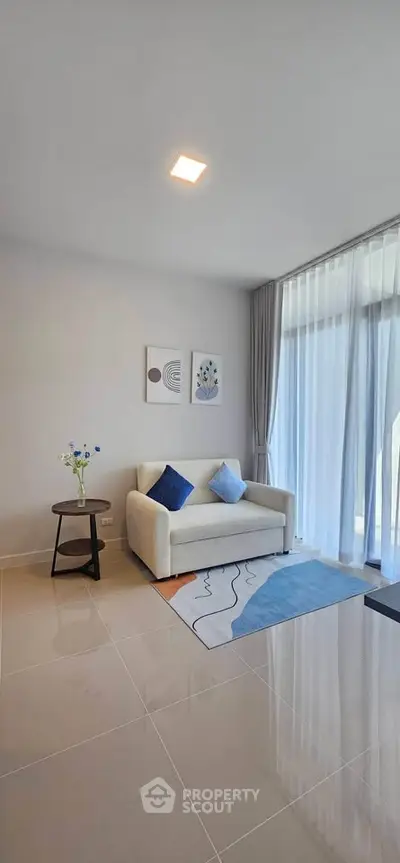 Modern living room with cozy sofa, elegant decor, and large window for natural light.