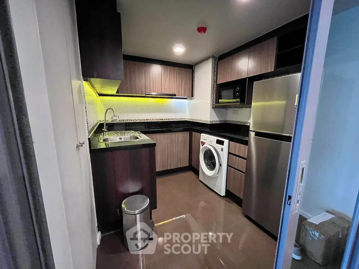 Modern kitchen with sleek cabinets, stainless steel appliances, and washing machine.