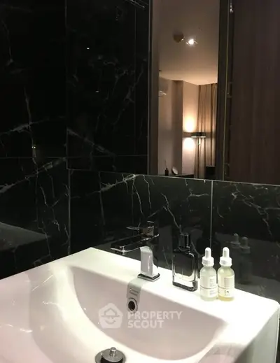 Luxurious bathroom with sleek black marble tiles and modern fixtures.