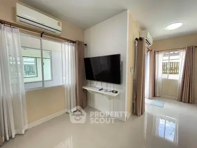 Modern living room with wall-mounted TV and large windows for natural light