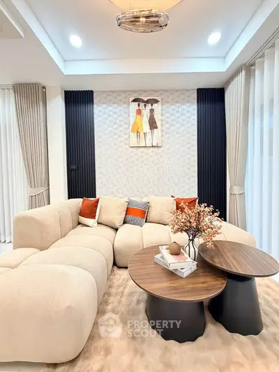 Elegant living room with plush beige sofa, modern coffee tables, and stylish decor accents.