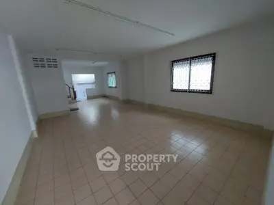 Spacious tiled room with natural light and barred windows, ideal for versatile use.