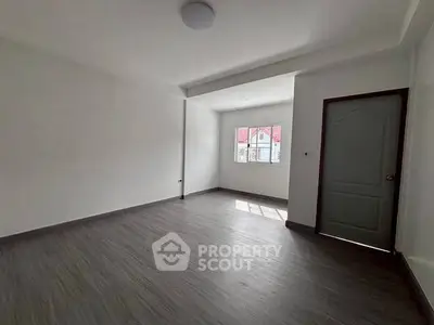 Spacious empty room with large window and wooden flooring