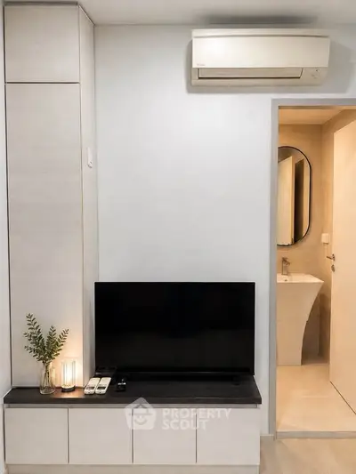 Modern living room with sleek TV unit and air conditioning, adjacent to a stylish bathroom.