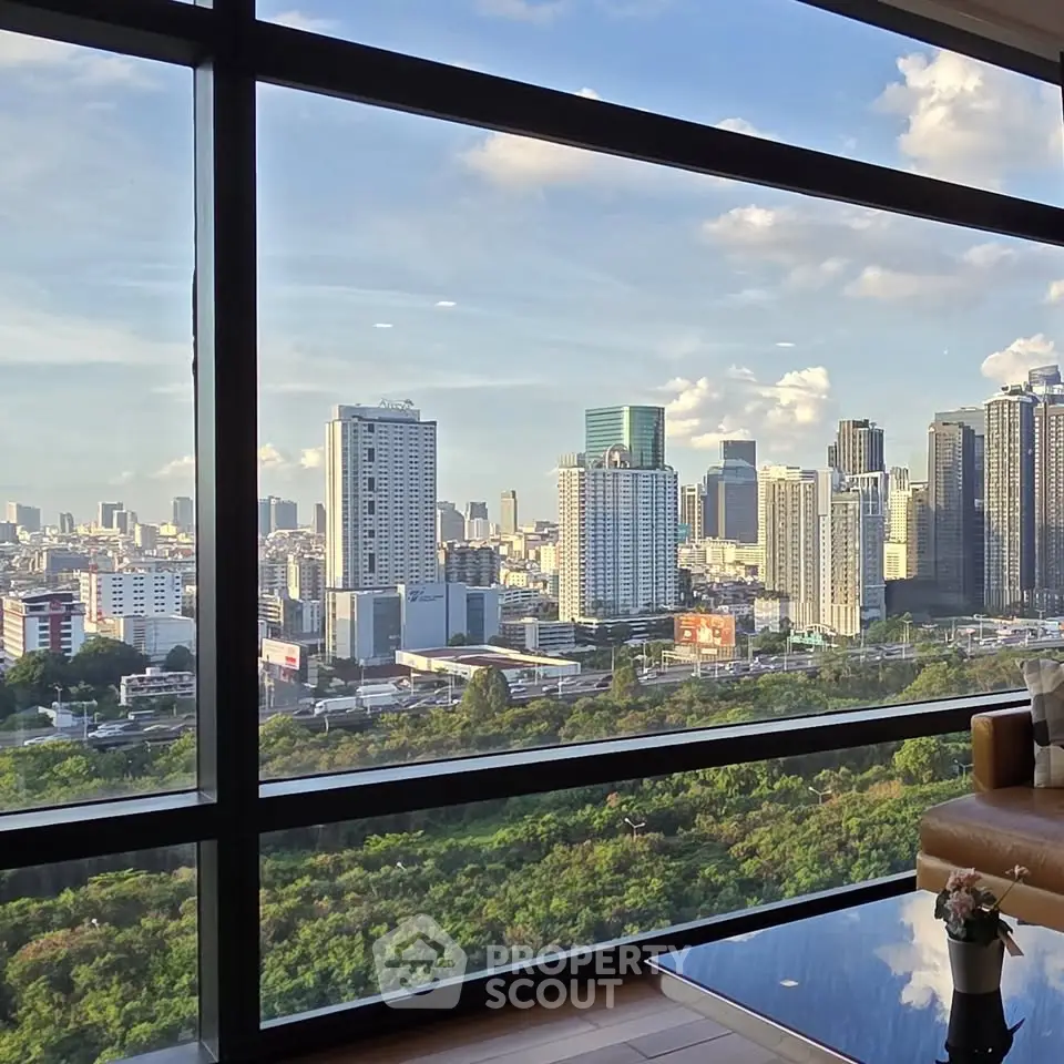 Stunning cityscape view from modern high-rise apartment window, showcasing urban skyline and lush greenery.