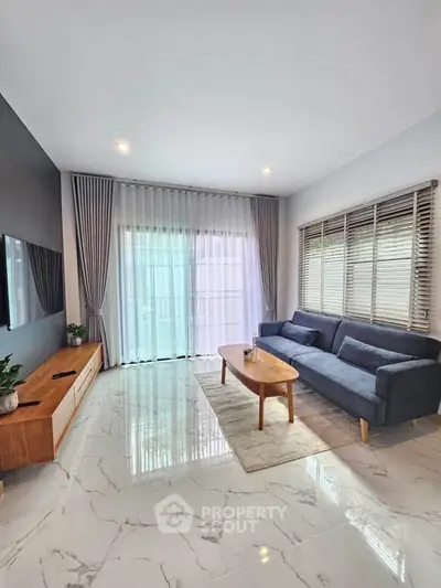 Modern living room with sleek furniture and large windows offering natural light.