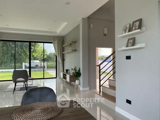 Modern living room with large windows and garden view, featuring stylish decor and open layout.