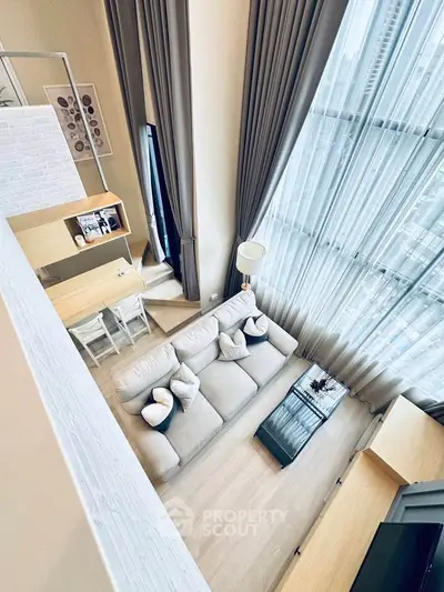 Modern loft-style living room with high ceilings and large windows offering city views.