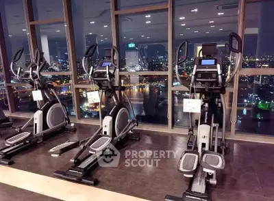 Luxurious gym with modern equipment and stunning city view from large windows.