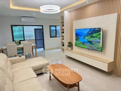 Modern living room with elegant decor, featuring a wall-mounted TV and stylish furniture.