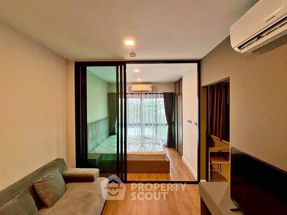 Modern studio apartment with glass partition, cozy living area, and air conditioning.