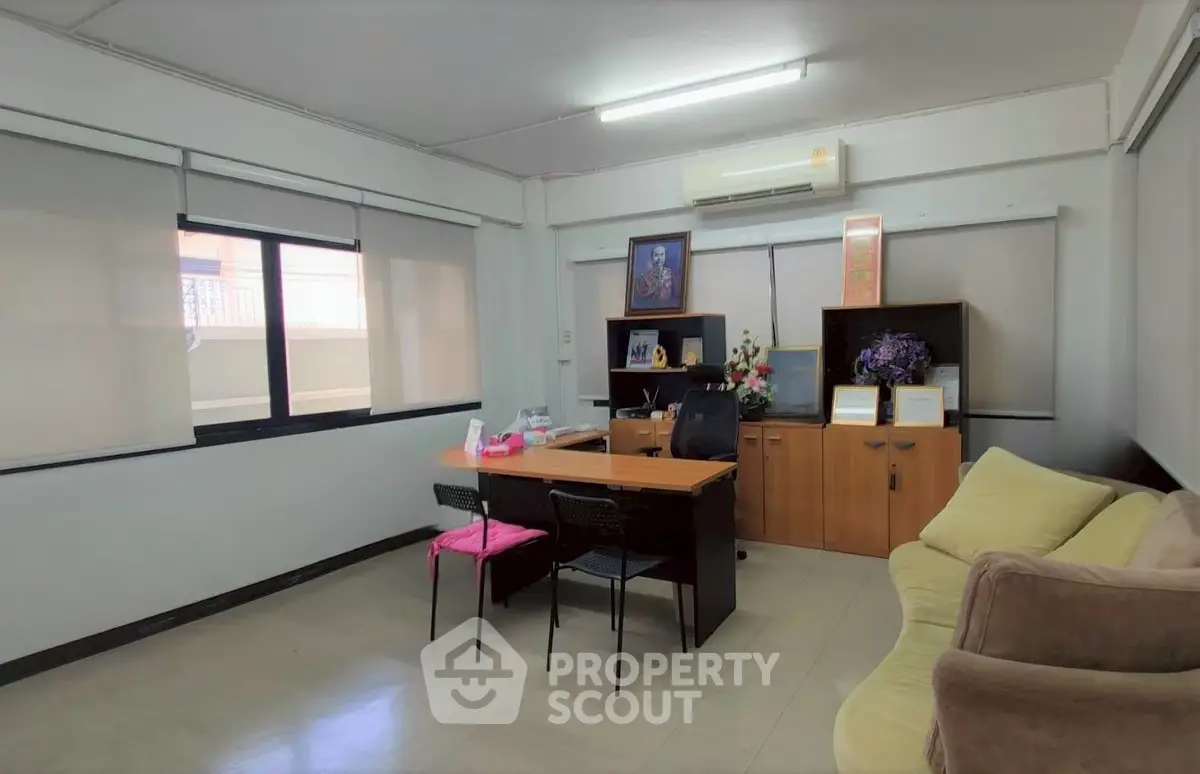 Spacious office room with desk, chairs, and sofa, ideal for professional work environment.