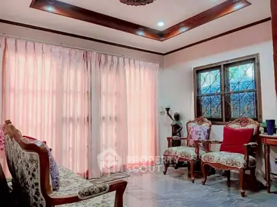Charming living room with elegant furniture and large windows with pink curtains.