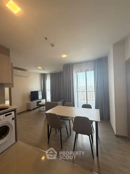 Modern living room with dining area and washing machine, featuring large windows and stylish decor.