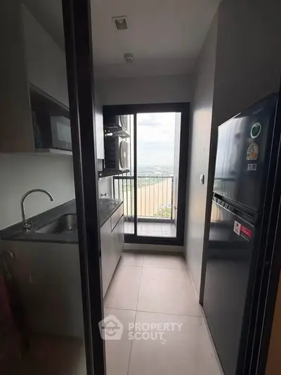 Modern kitchen with sleek appliances and balcony view in high-rise apartment.