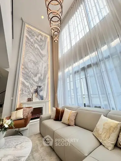 Luxurious living room with high ceilings, elegant chandelier, and marble accent wall.